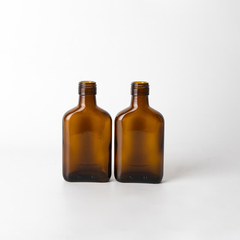 Petite bouteille alcoolisée en verre ambre plat avec finition à vis
